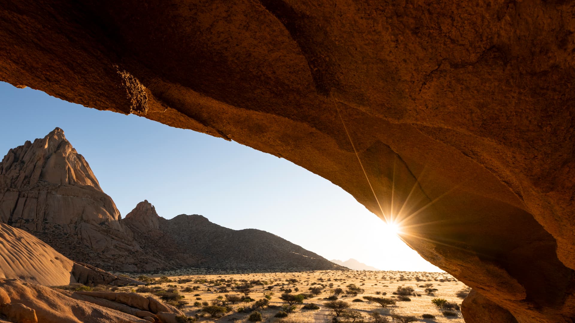 A weathered natural rock arch in ancient Namibian landscape