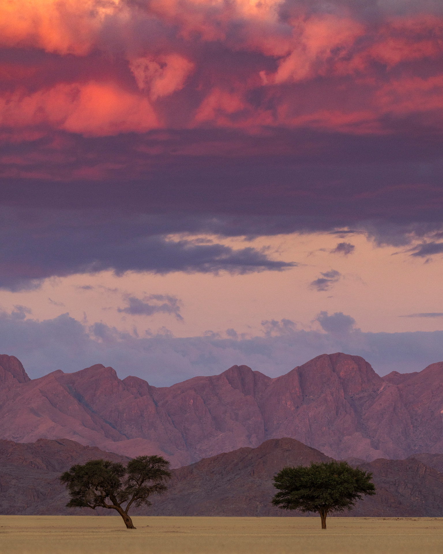 A pink and violet Namibian sky at dusk over desert mountains